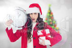 Composite image of surprised brunette holding a clock and gift