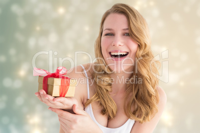 Composite image of smiling young woman holding a small gift
