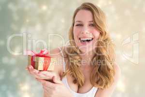 Composite image of smiling young woman holding a small gift