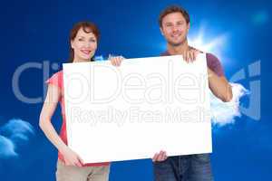 Composite image of couple holding a white sign