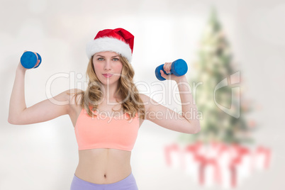 Composite image of festive fit blonde holding dumbbells