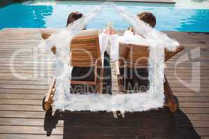 Composite image of couple toasting champagne by swimming pool