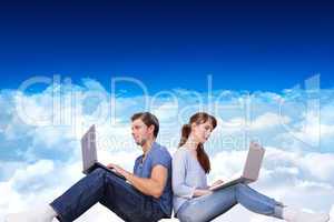 Composite image of couple both using laptops separately