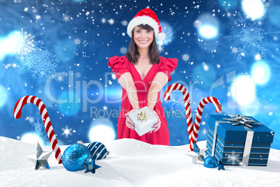 Composite image of festive brunette giving a gift