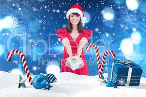 Composite image of festive brunette giving a gift