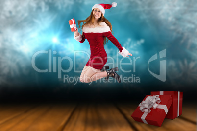 Composite image of festive redhead jumping with gift