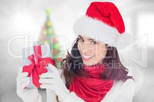 Composite image of excited brunette in santa hat showing gift