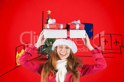 Composite image of festive redhead holding pile of gifts