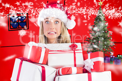 Composite image of festive blonde holding pile of gifts