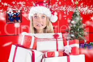 Composite image of festive blonde holding pile of gifts