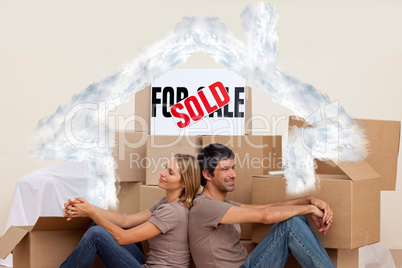 Composite image of happy couple sitting on floor after buying ho