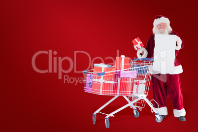 Composite image of santa spread presents with shopping cart