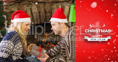 Composite image of man gifting woman in front of lit fireplace d