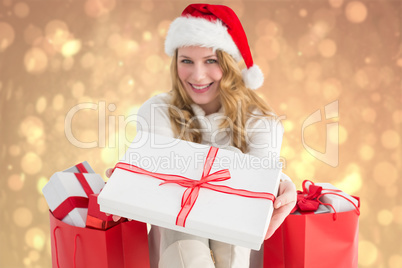 Composite image of woman in santa hat offering a gift