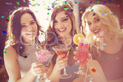 Composite image of attractive friends drinking cocktails togethe