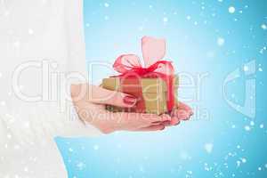 Composite image of pretty woman holding gild gift