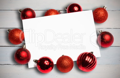 Composite image of red christmas baubles surrounding white page