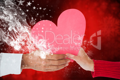 Composite image of couple holding heart