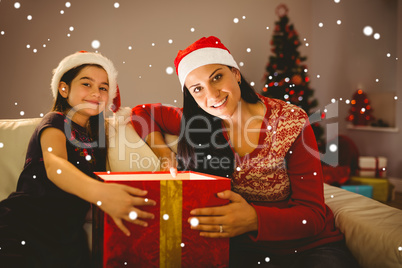 Composite image of festive mother and daughter opening a glowing