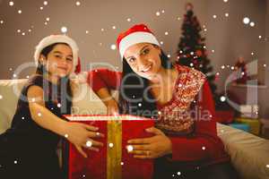 Composite image of festive mother and daughter opening a glowing