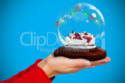 Composite image of hand holding santa snow globe