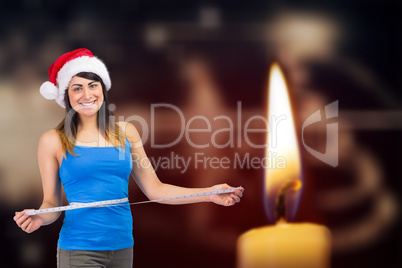 Composite image of festive fit brunette measuring her waist