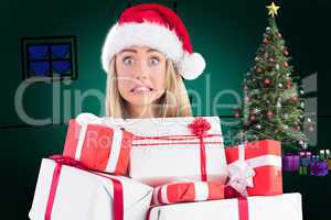 Composite image of festive blonde holding pile of gifts