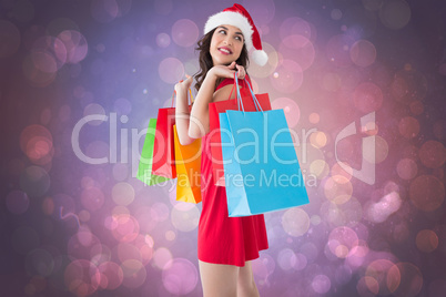 Composite image of festive brunette holding shopping bags