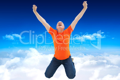 Composite image of mature man in orange tshirt cheering while kn