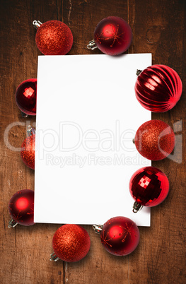 Composite image of red christmas baubles surrounding white page