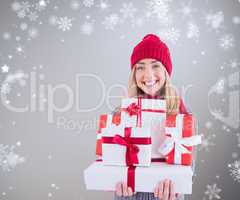 Composite image of festive blonde holding pile of gifts