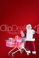 Composite image of santa spread presents with shopping cart