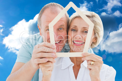 Composite image of happy older couple holding house shape Composite image of happy older couple holding house shape