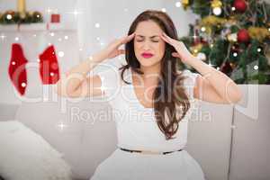 Composite image of brunette getting a headache on christmas day