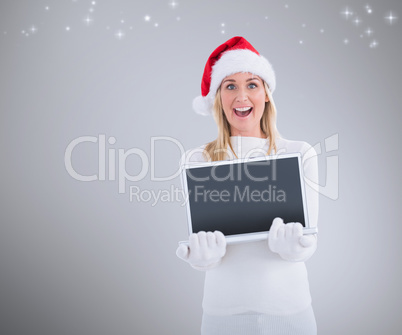 Composite image of festive blonde showing a laptop