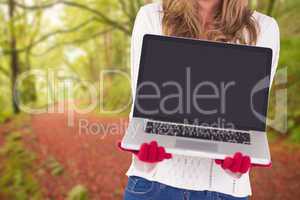 Composite image of festive blonde showing a laptop
