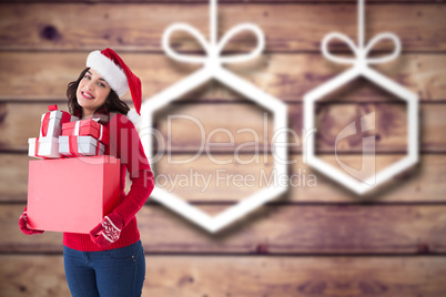 Composite image of happy brunette in santa hat holding many gift
