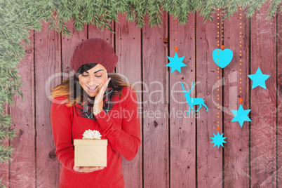 Composite image of surprised brunette holding a gift