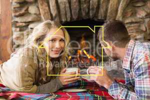 Composite image of couple with tea cups in front of lit fireplac