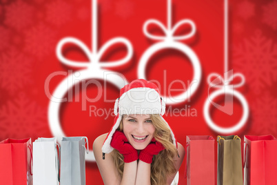 Composite image of smiling woman lying between shopping bags