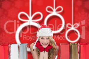 Composite image of smiling woman lying between shopping bags