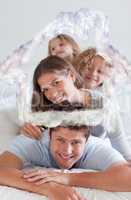 Composite image of portrait of a joyful family lying on each oth