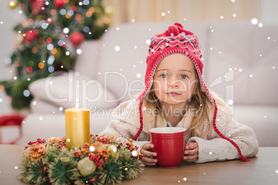 Composite image of cute little girl holding mug at christmas