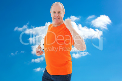 Composite image of mature man in orange tshirt cheering holding