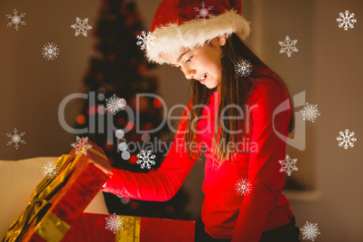 Composite image of festive little girl opening a glowing christm