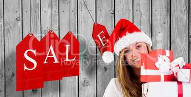 Composite image of festive blonde holding pile of gifts