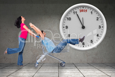 Composite image of young couple having fun with shopping cart