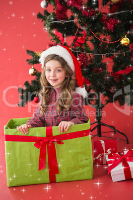 Composite image of festive little girl sitting in large gift