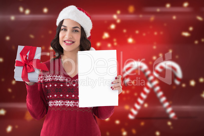 Composite image of festive brunette holding gift and showing pap
