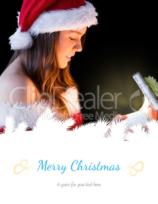 Composite image of pretty brunette in santa outfit opening gift